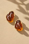 Amber resin stone gold earrings on beige backdrop