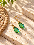 Green teardrop fishhook earrings on sunlit travertine