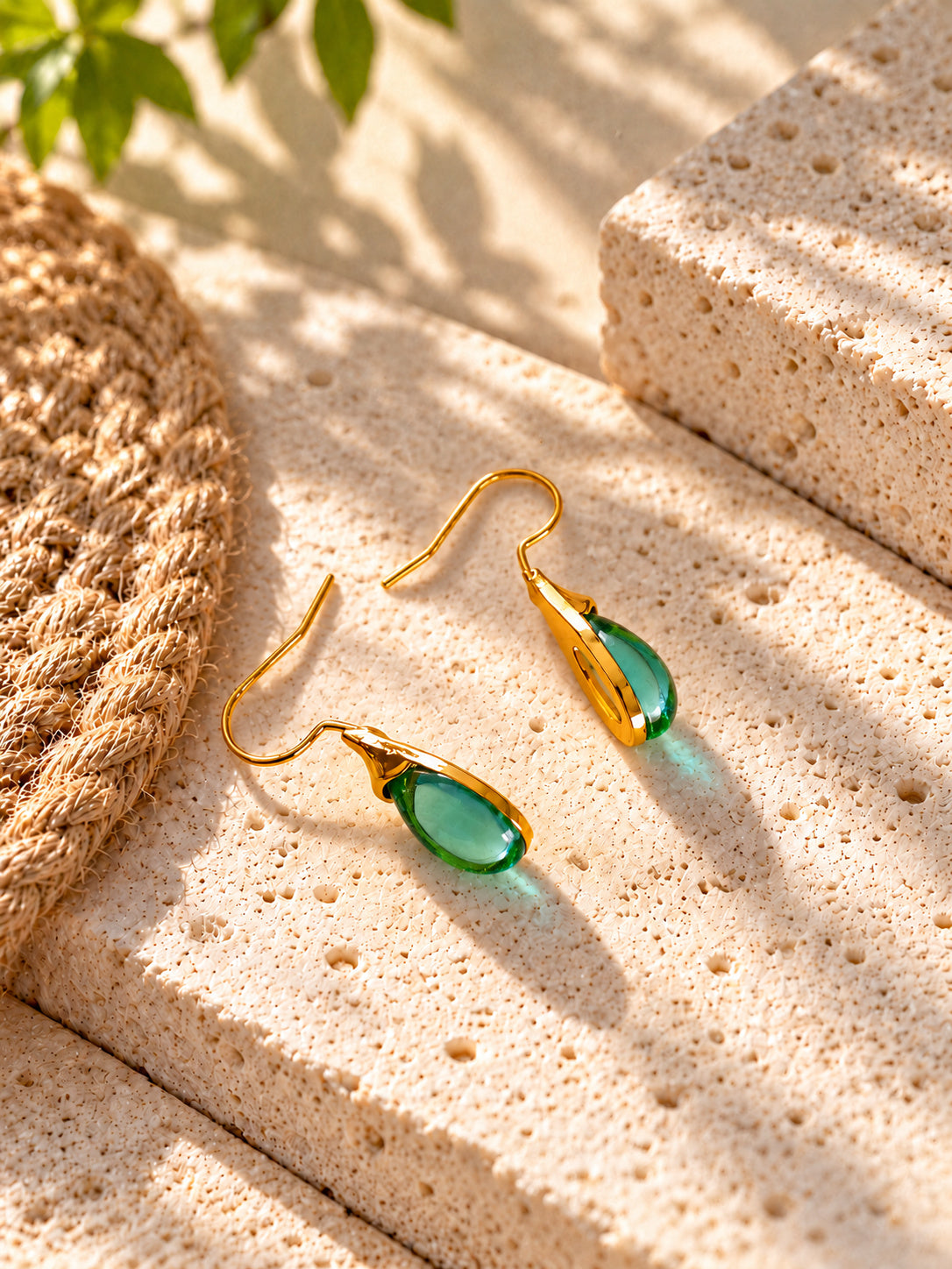 Green teardrop earrings on travertine