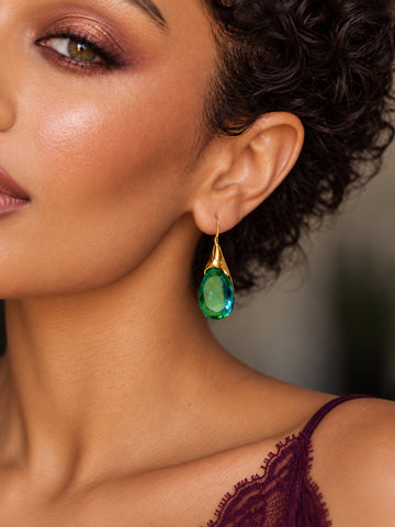 Green teardrop earrings worn in an editorial portrait