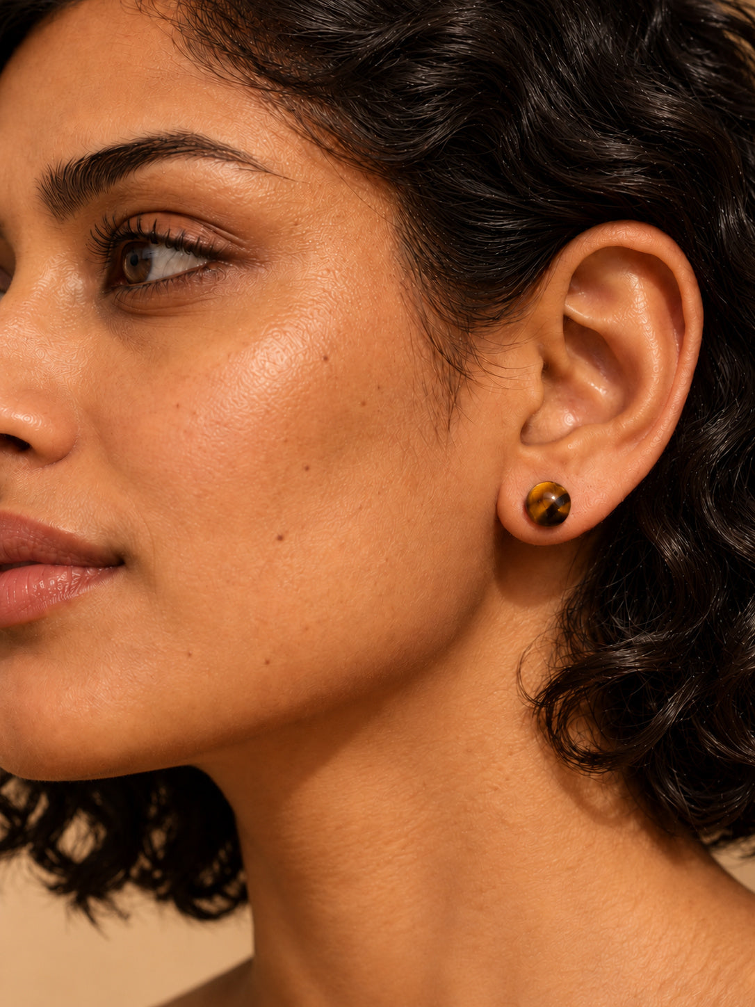 Amber brown round stud earrings on sunlit travertine — view 1
