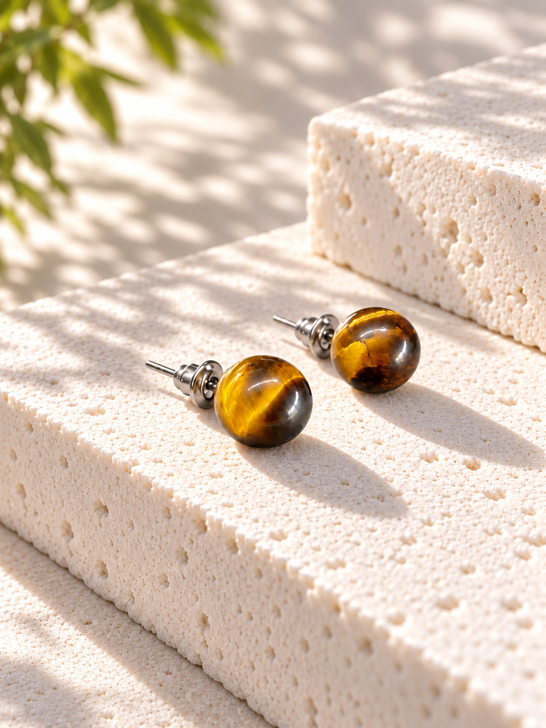 Amber brown round stud earrings on sunlit travertine — view 2
