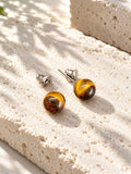 Amber brown round stud earrings on sunlit travertine — view 3