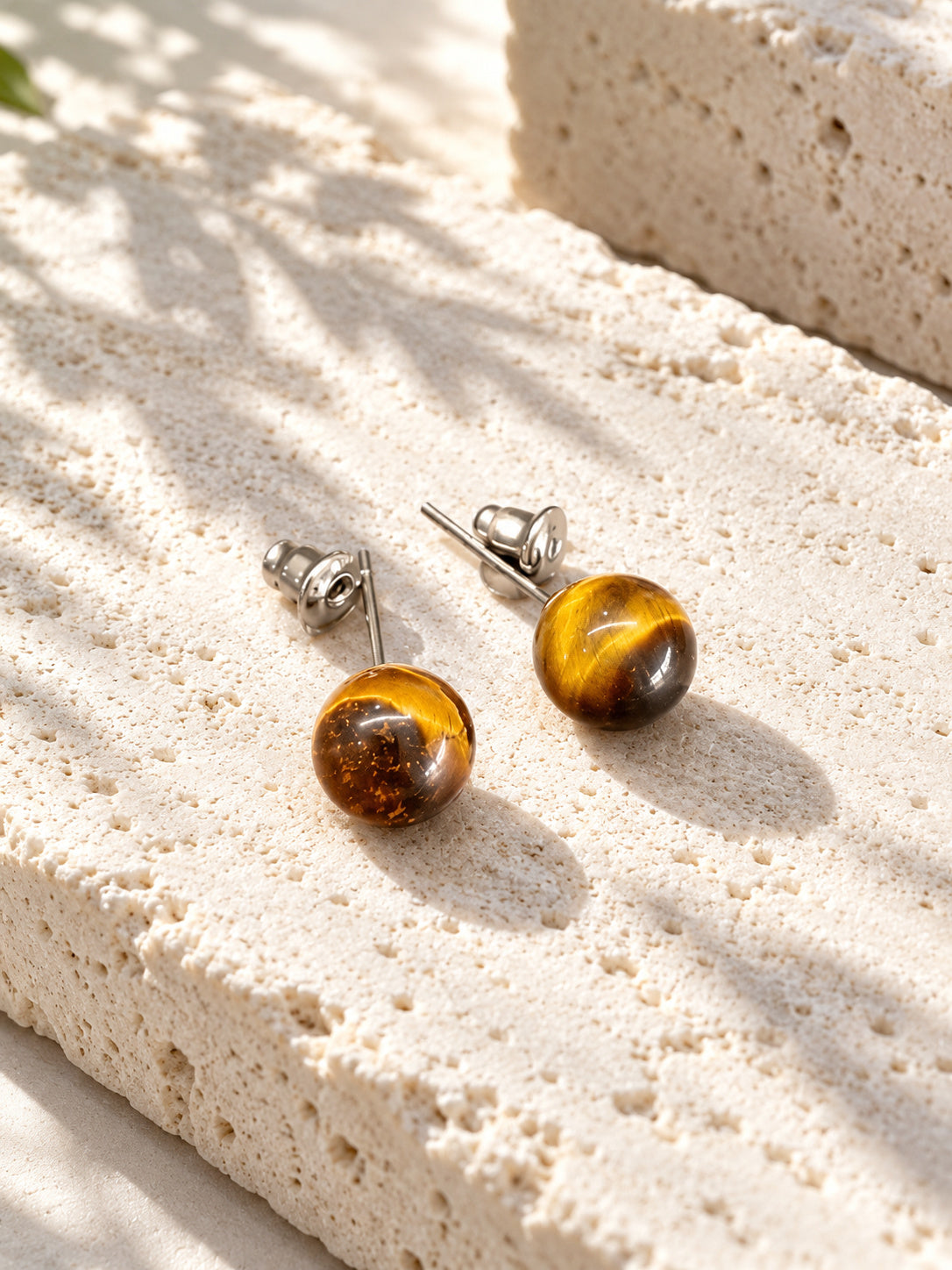 Amber brown round stud earrings on sunlit travertine — view 3
