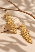 Gold statement earrings on cream stone