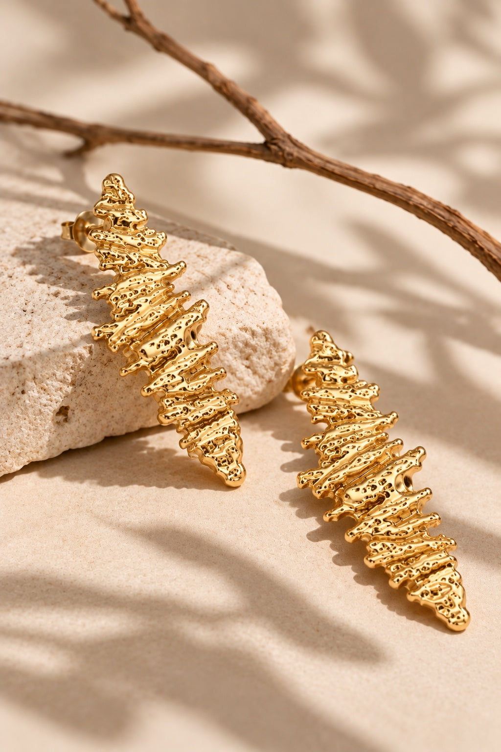 Gold statement earrings on cream stone