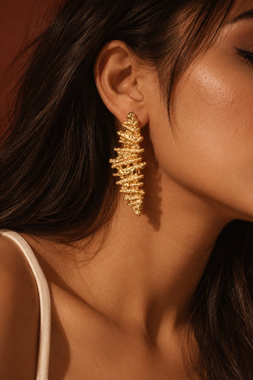 Model wearing textured gold statement earring