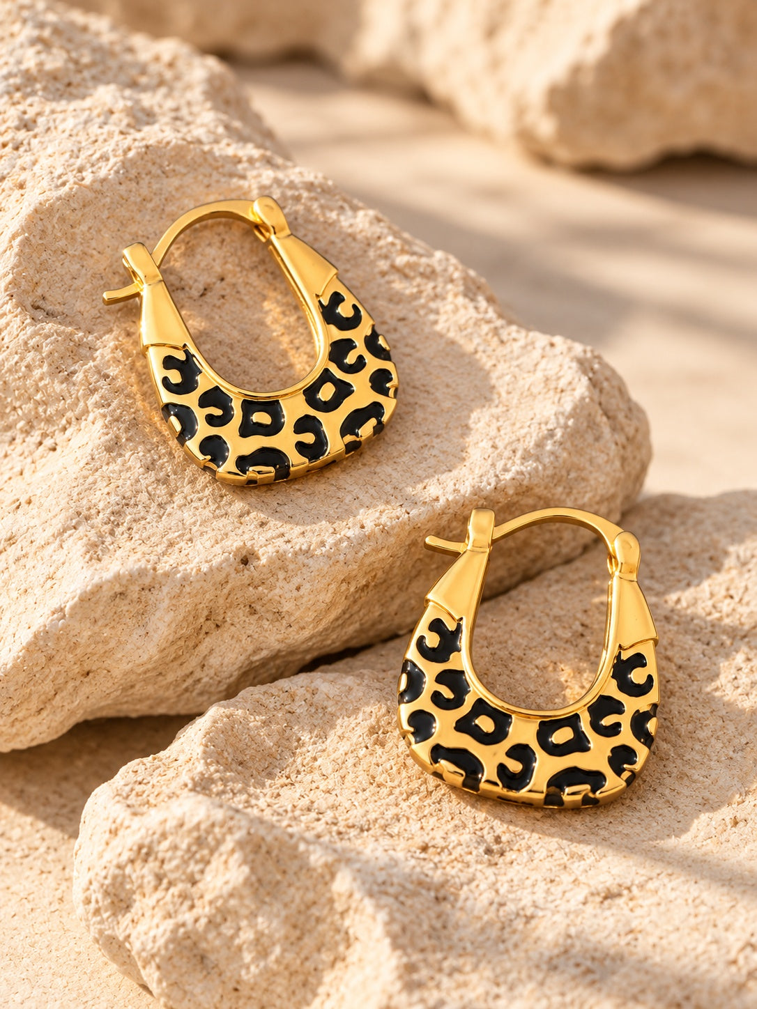 Gold leopard-print hoop earrings on limestone