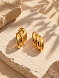 Sculpted gold earrings on textured stone backdrop