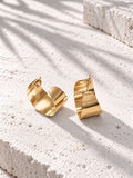 Niska gold-tone sculptural alloy hoop earrings on white travertine