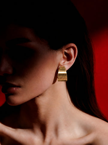 Niska gold-tone sculptural hoop earring worn by model