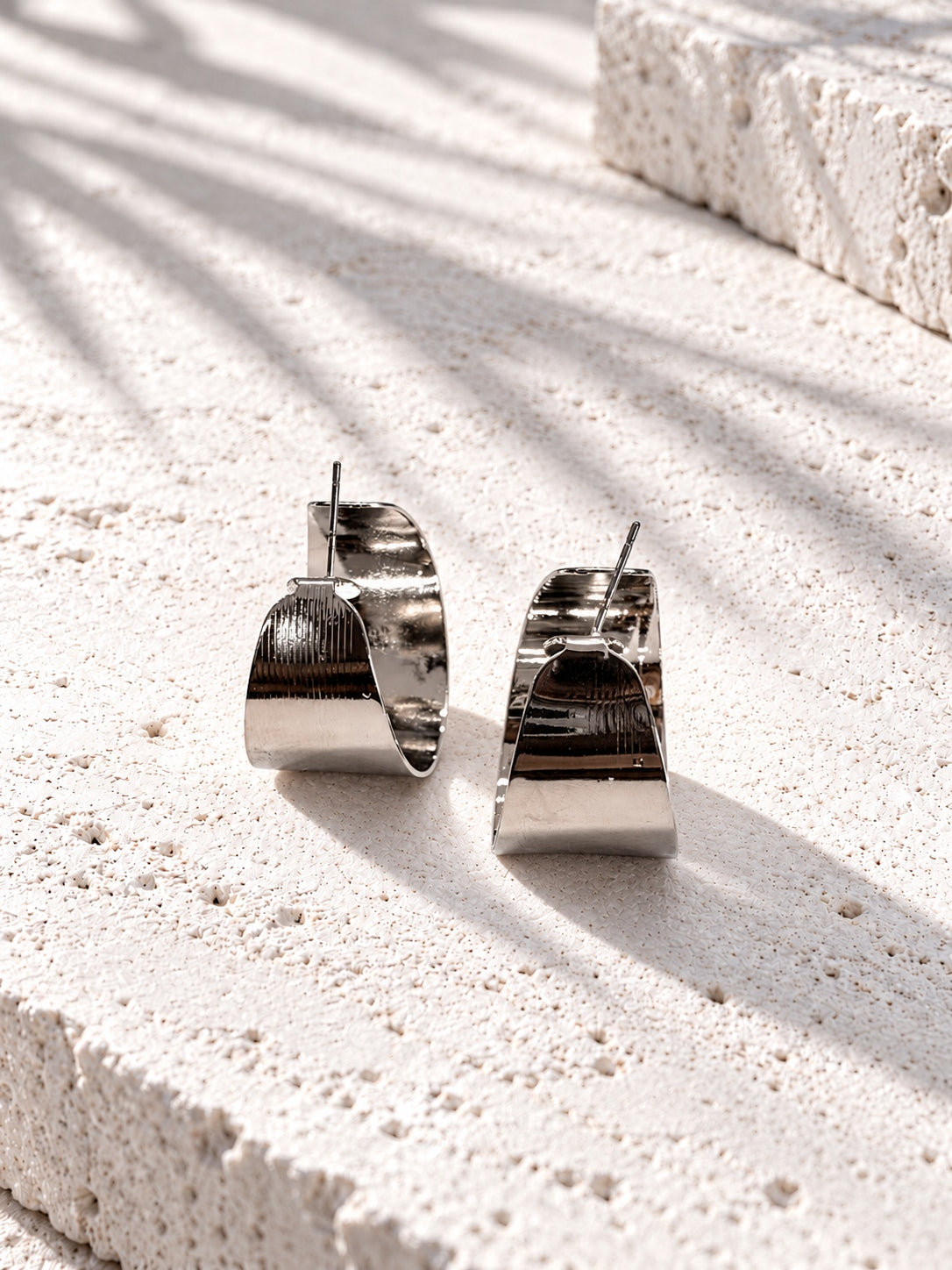 Niska silver-tone sculptural hoop earring worn by model