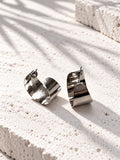 Niska silver-tone alloy statement hoop earrings on white travertine