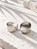 Niska silver-tone alloy statement hoop earrings on white travertine