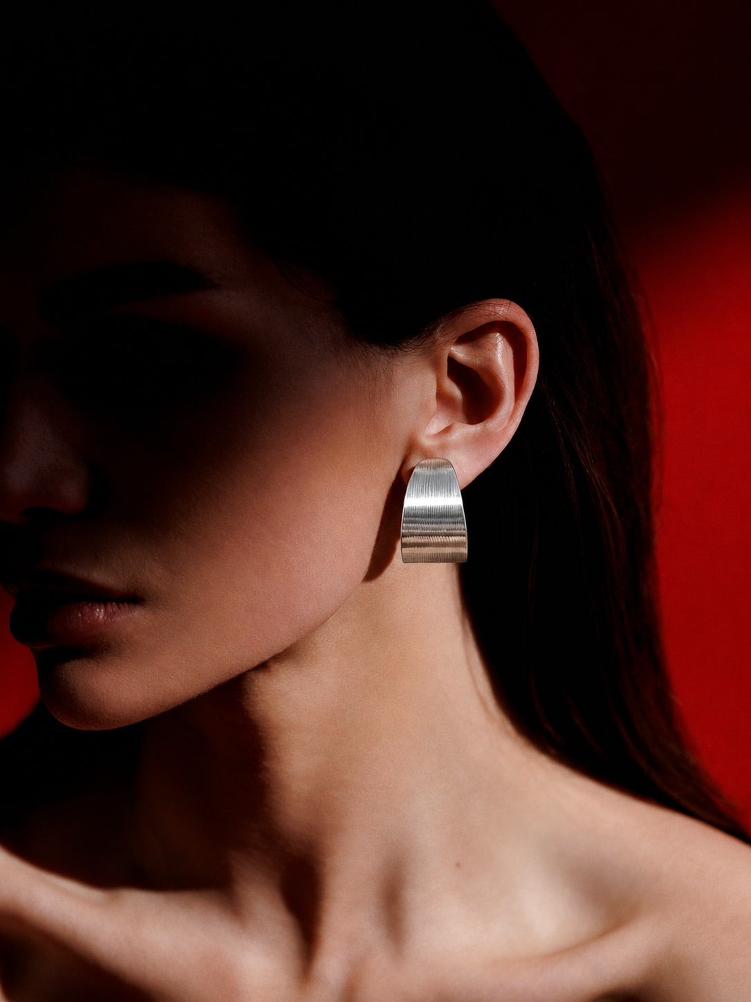 Niska silver-tone sculptural hoop earring worn by model