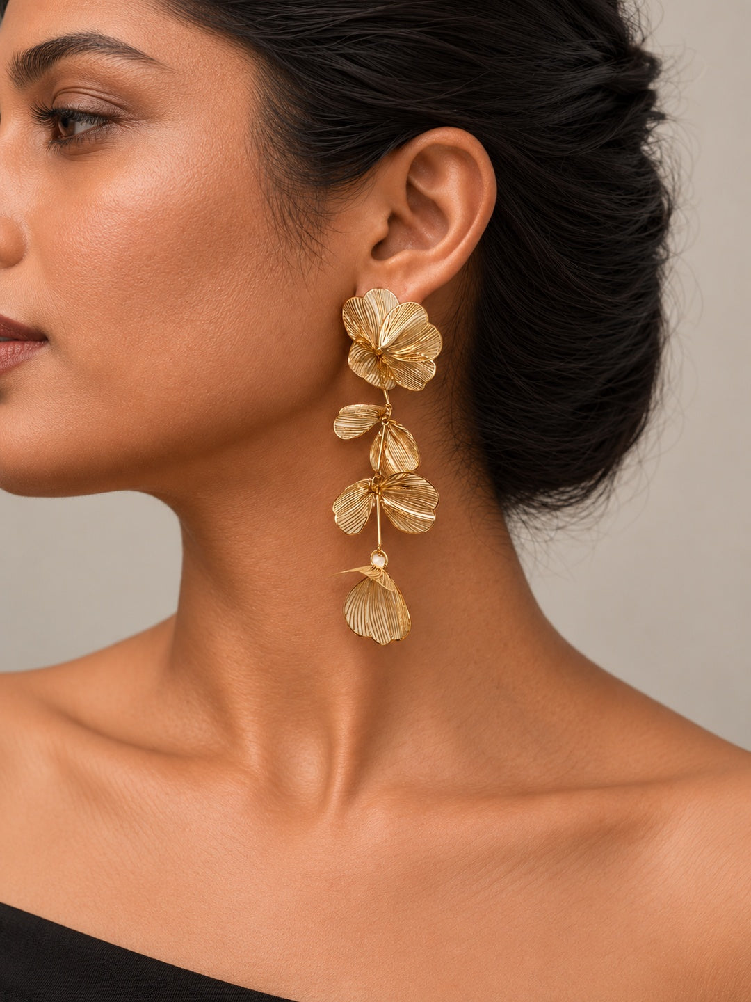Gold-tone floral petal drop earrings worn on model