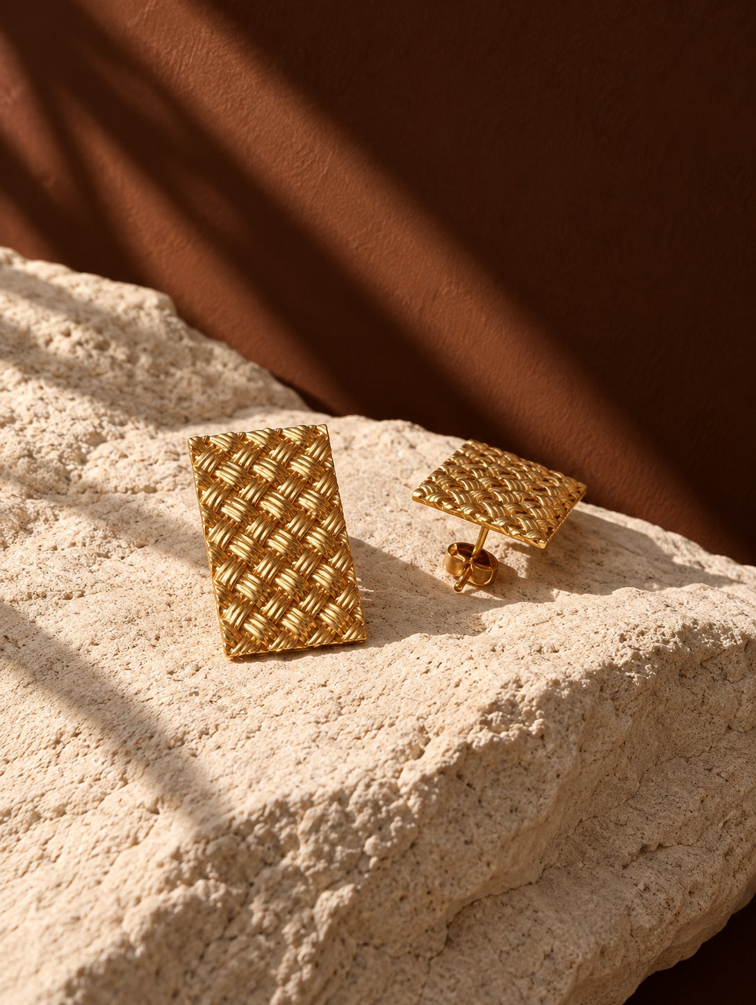 Gold woven rectangular earrings, product still life