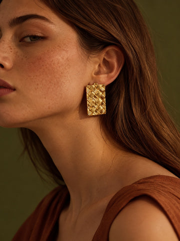 Model wearing gold woven rectangular earrings