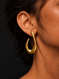 Niska sculptural gold-tone open teardrop earring worn by model, close-up