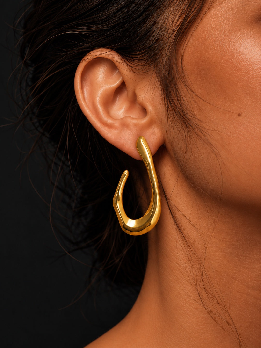 Niska sculptural gold-tone open teardrop earring worn by model, close-up