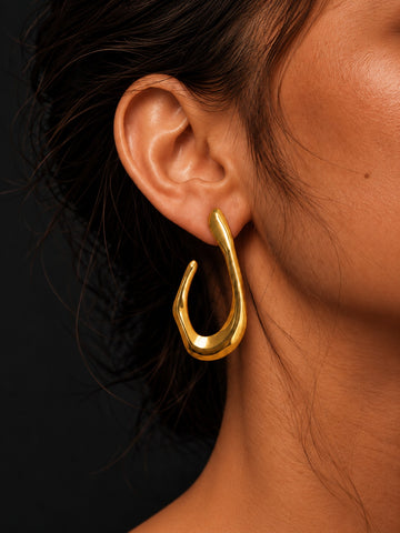 Niska sculptural gold-tone open teardrop earring worn by model, close-up