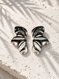 Niska silver-tone sculptural wave statement earrings on white stone