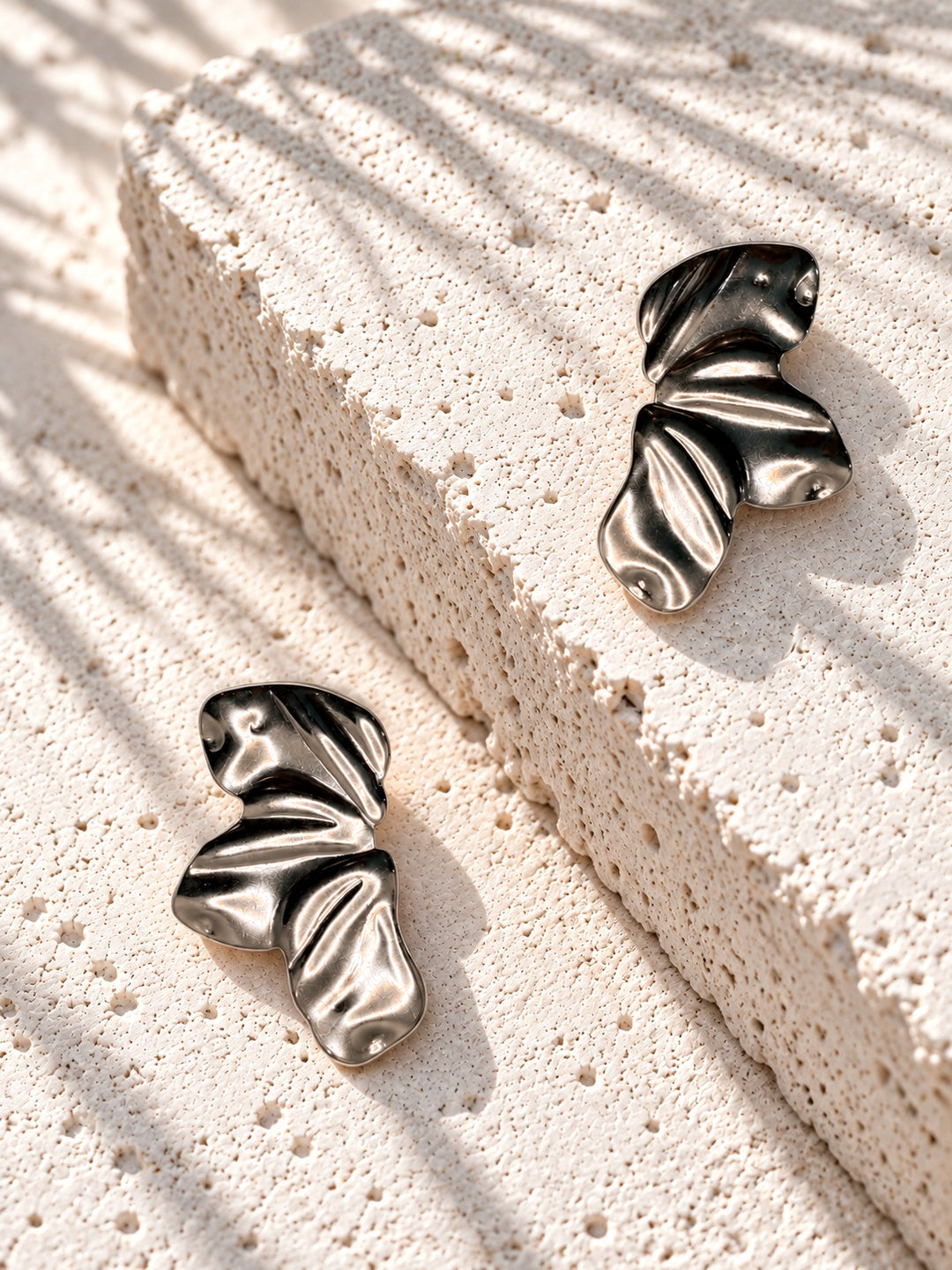 Niska statement earrings on raised white travertine slab