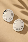 Concentric oval statement earrings on beige textured backdrop