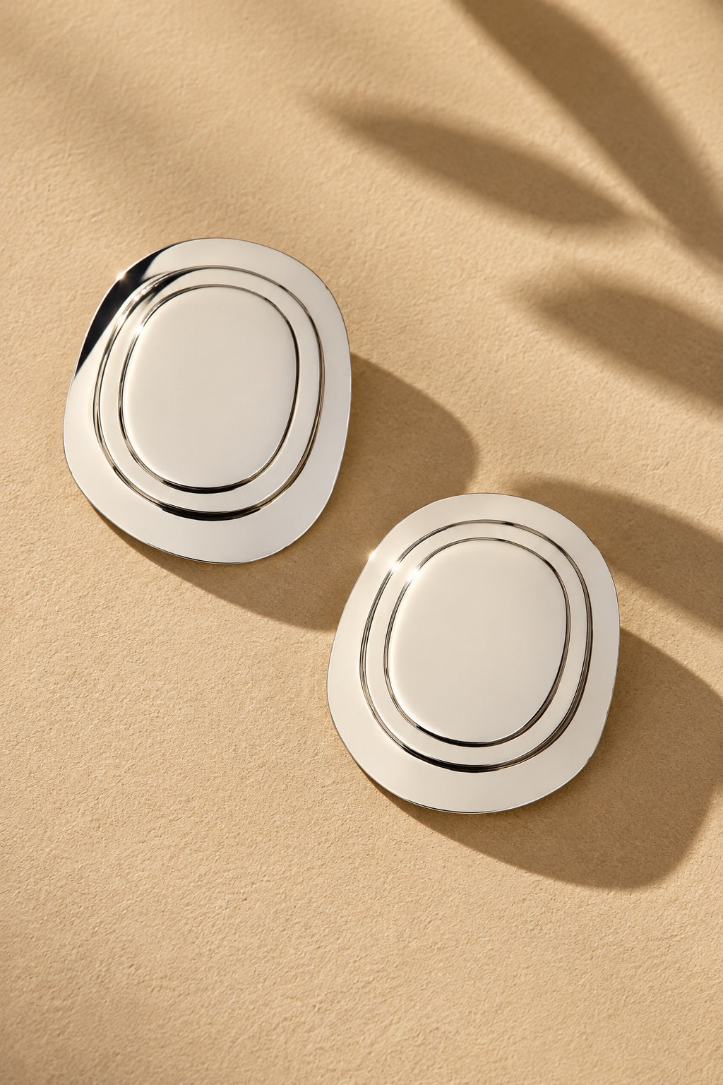 Concentric oval statement earrings on beige textured backdrop