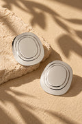 Silver oval statement earrings styled beside textured stone