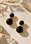 Black double sphere earrings on cream stone backdrop