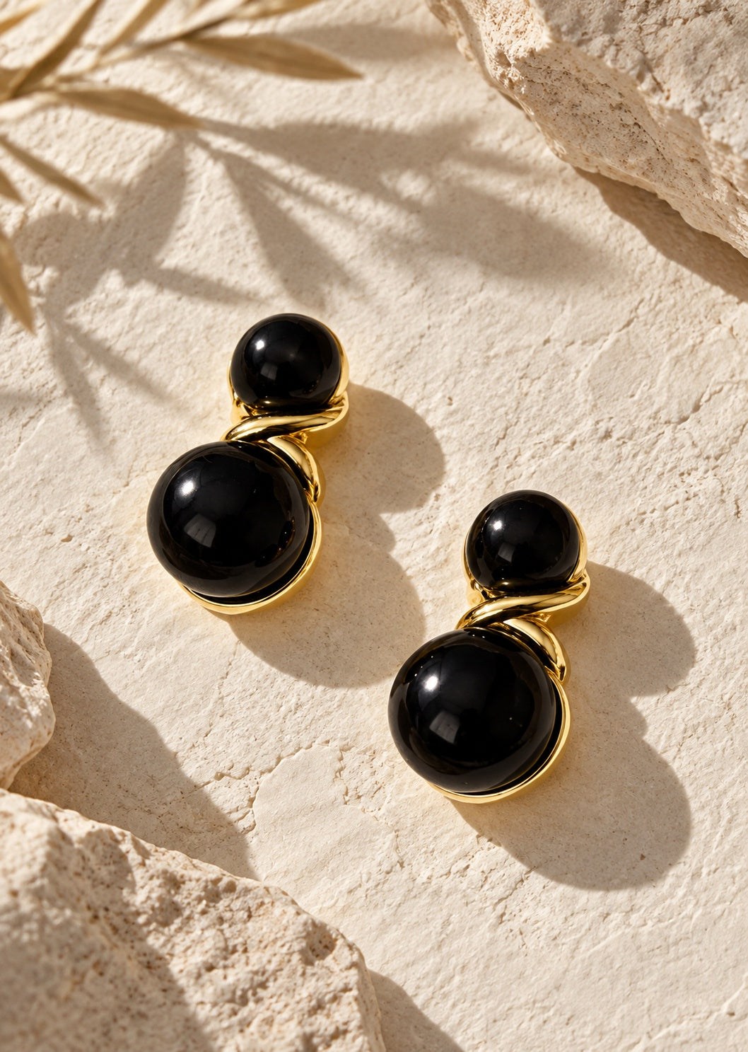 Black double sphere earrings on cream stone backdrop
