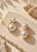 White pearl double-sphere earrings on neutral textured backdrop
