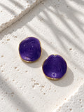 Niska purple spiral statement stud earrings on white travertine
