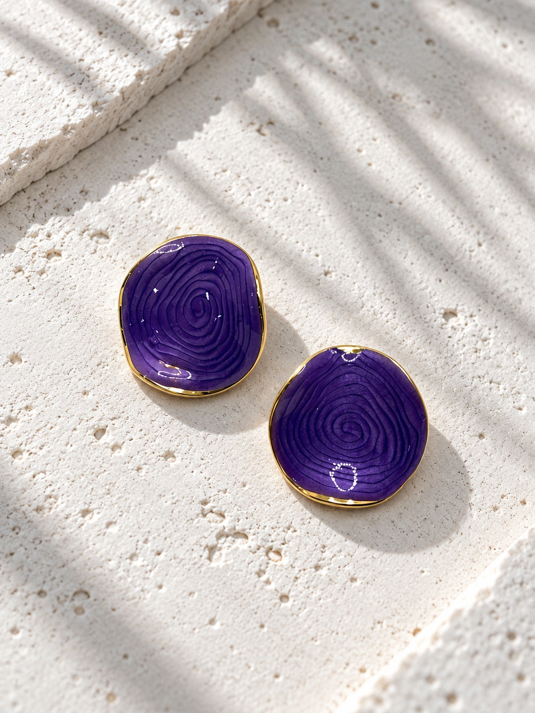 Niska purple spiral statement stud earrings on white travertine
