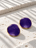 Niska purple spiral statement stud earrings on white travertine