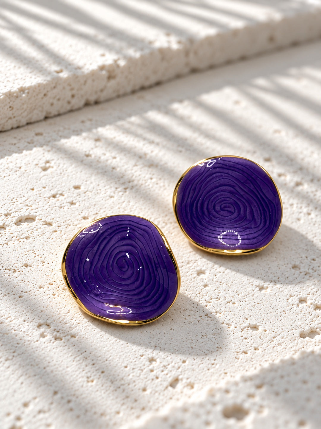Niska purple spiral statement stud earrings on white travertine