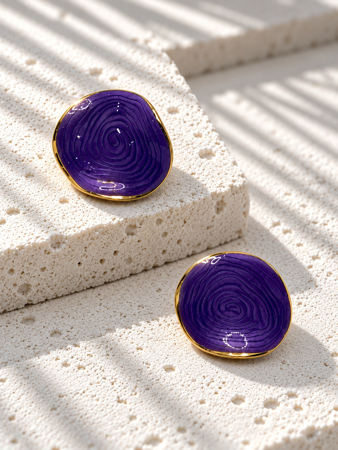 Niska purple spiral statement stud earrings on white travertine