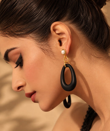Model wearing pearl and black resin long drop earrings