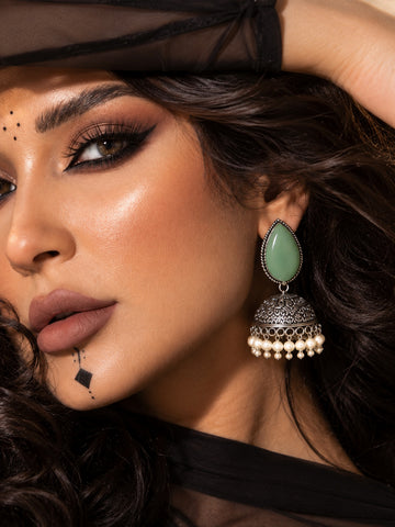 Close-up model wearing Monalisa green stone oxidized jhumka earrings