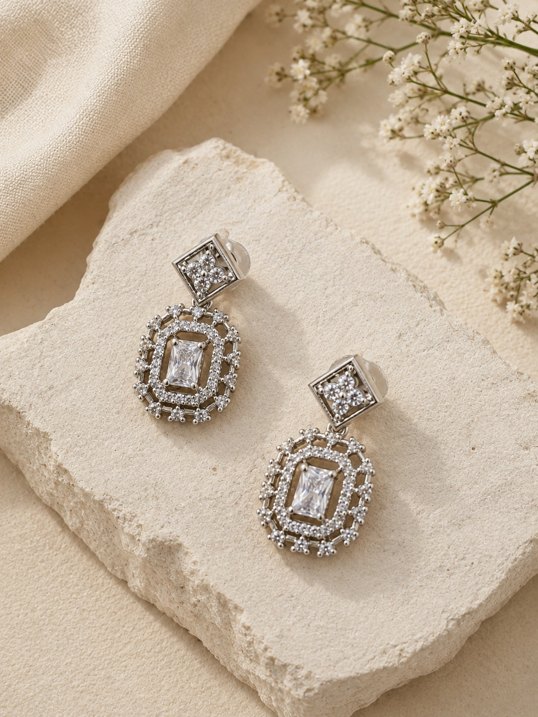 Silver AD stone replica drop earrings close-up flat lay