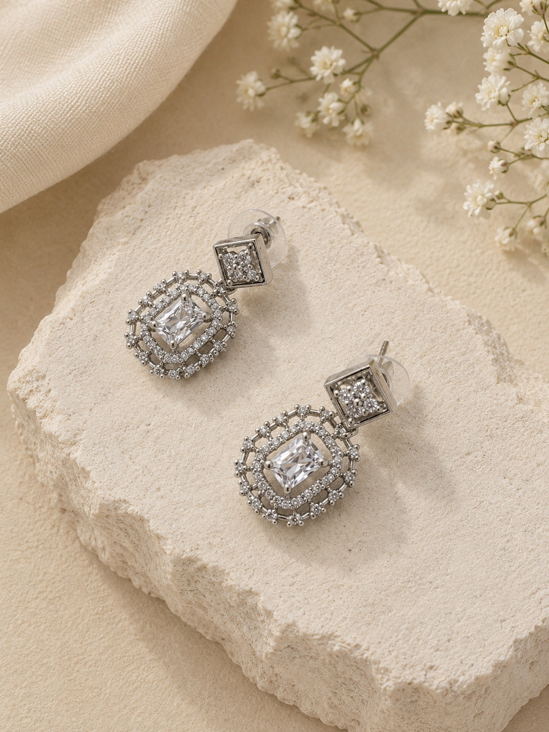 Silver AD stone replica drop earrings on textured stone
