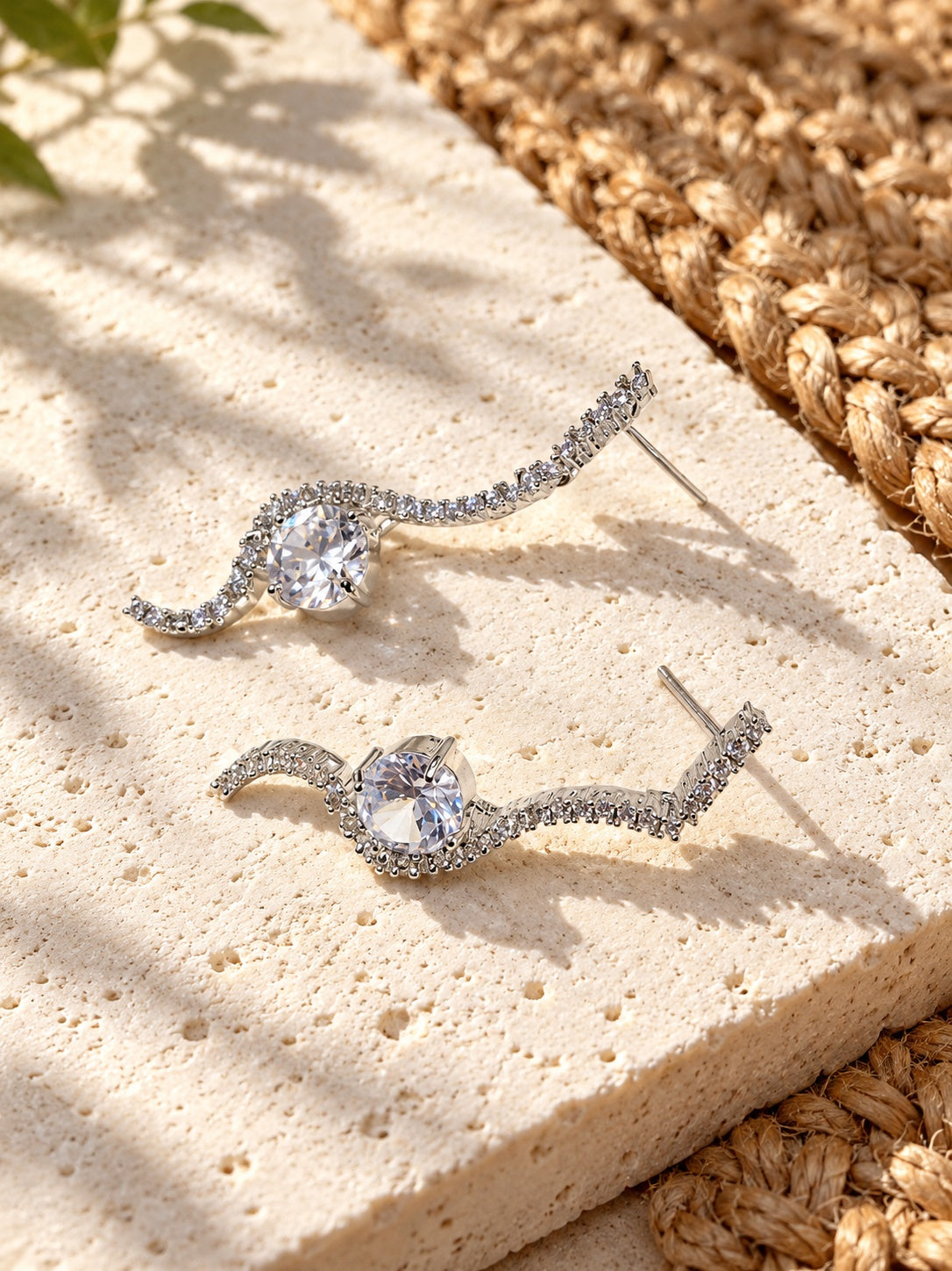 Niska AD Stone Silver Replica curved drop earrings on white travertine