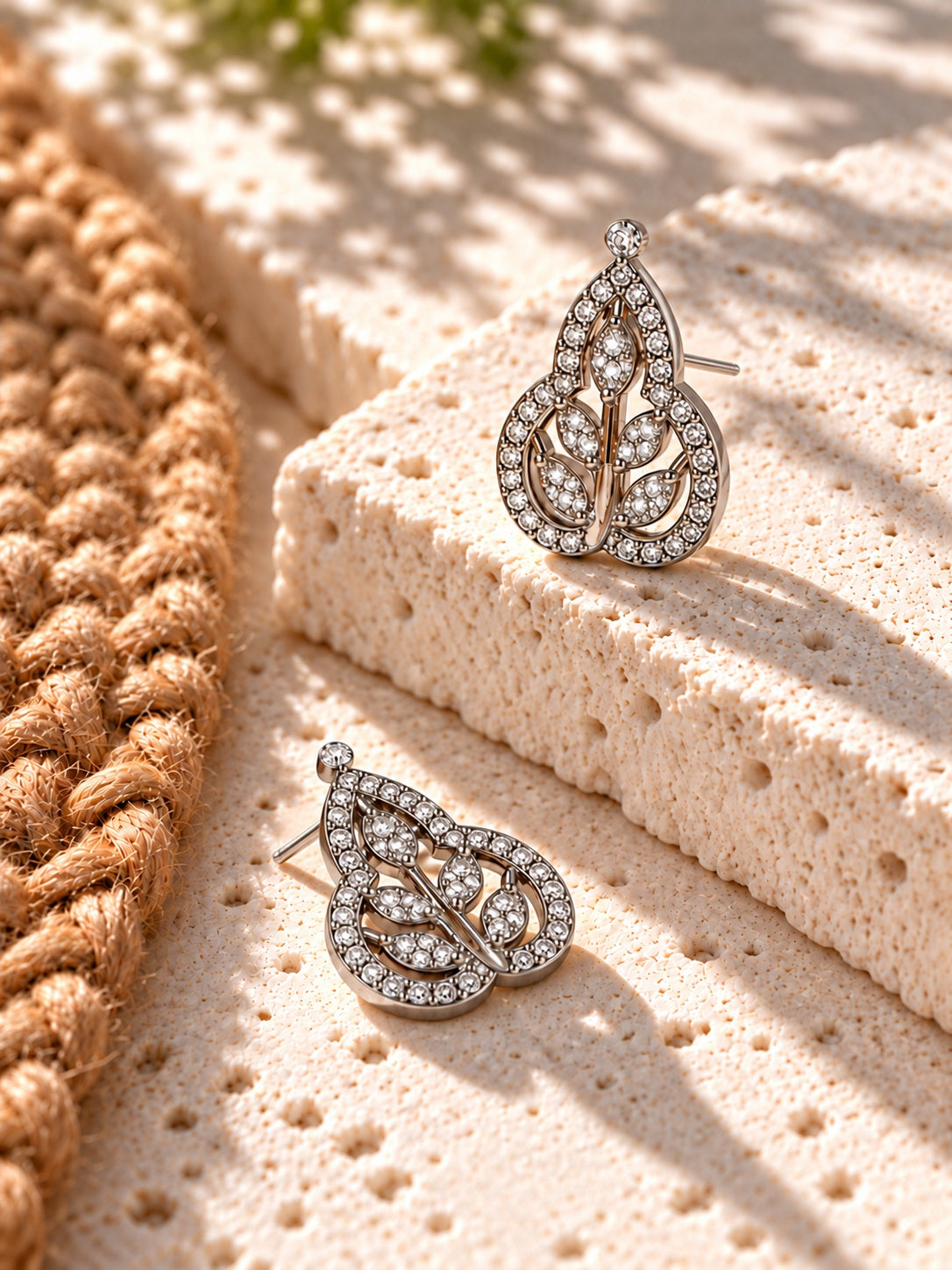 Niska AD Stone Silver Replica leaf earrings with stud posts on white travertine