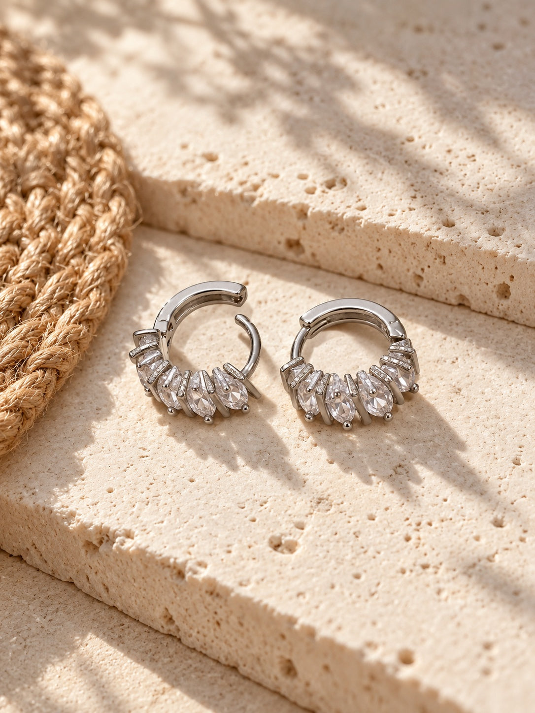 Niska Silver replica white AD Stone hoop earrings on white travertine with jute mat