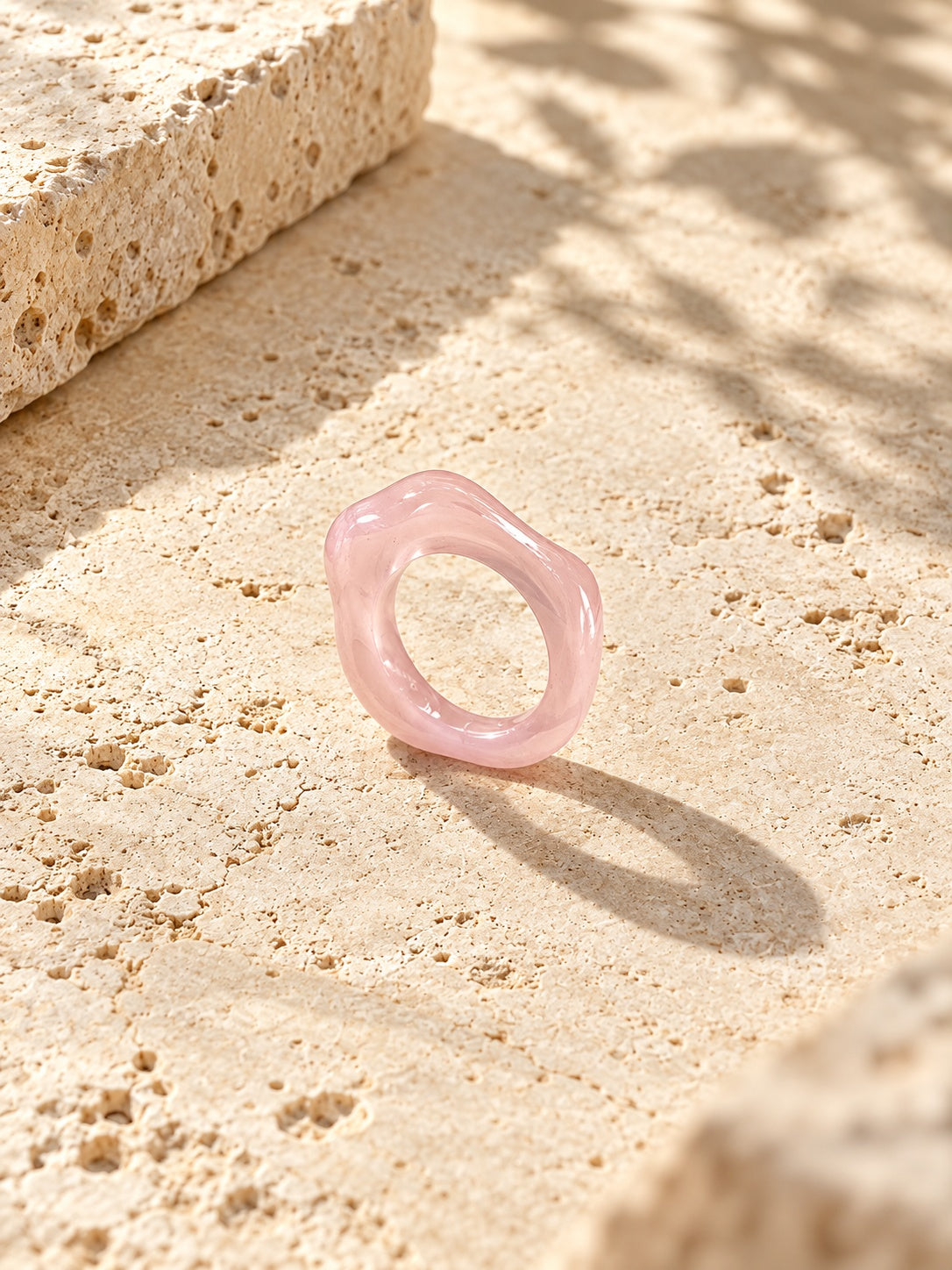 Blush pink sculpted replica ring on sunlit ivory travertine