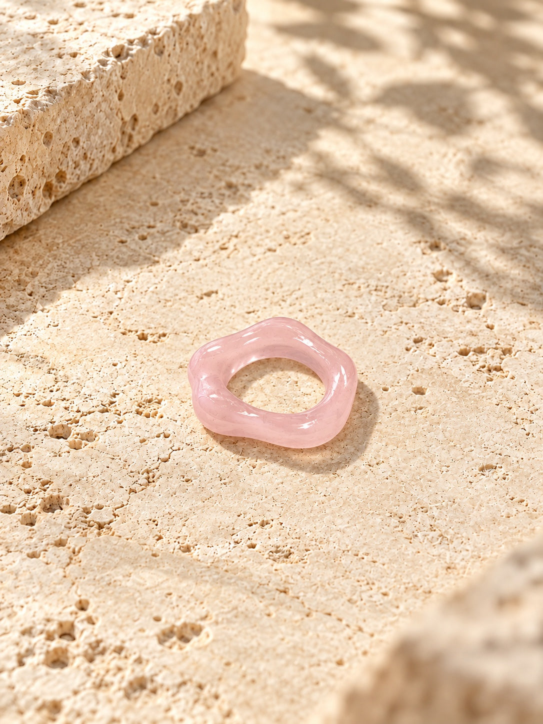 Blush pink sculpted replica ring on sunlit ivory travertine