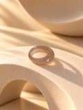 Taupe chunky resin replica ring on textured stone, view 2