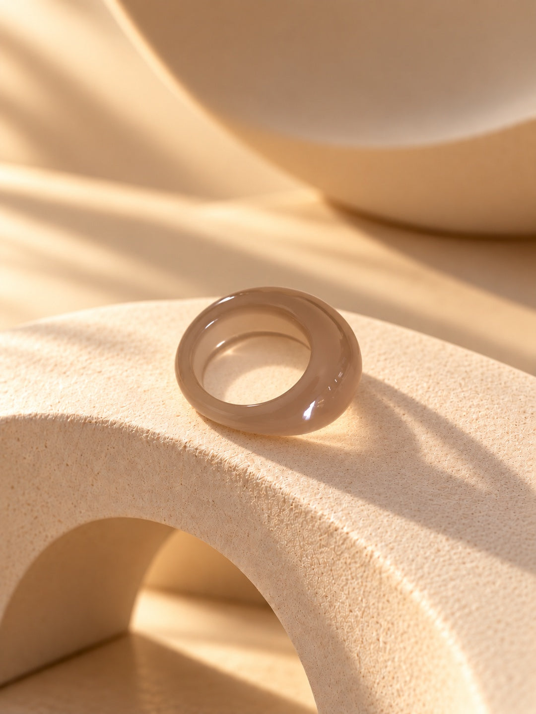 Taupe chunky resin replica ring on textured stone, view 5