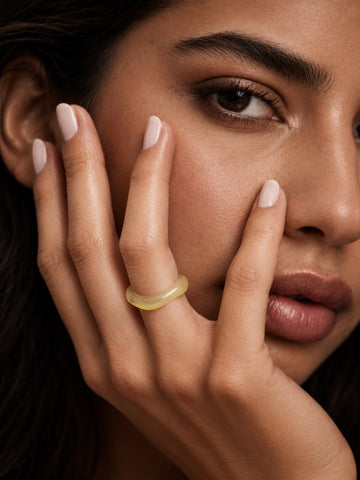 Pale yellow sculptural replica ring worn on a model's hand